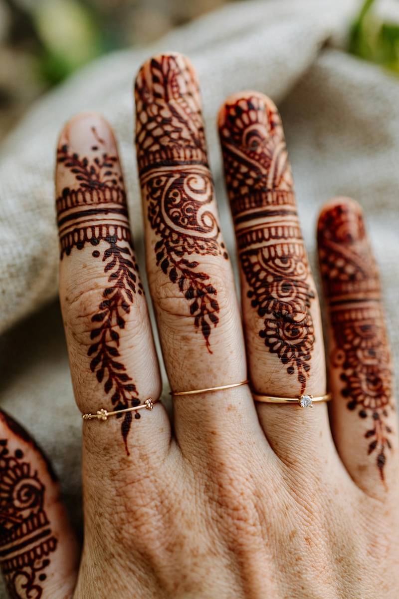 Intricate bridal henna bands covering bride's fingers