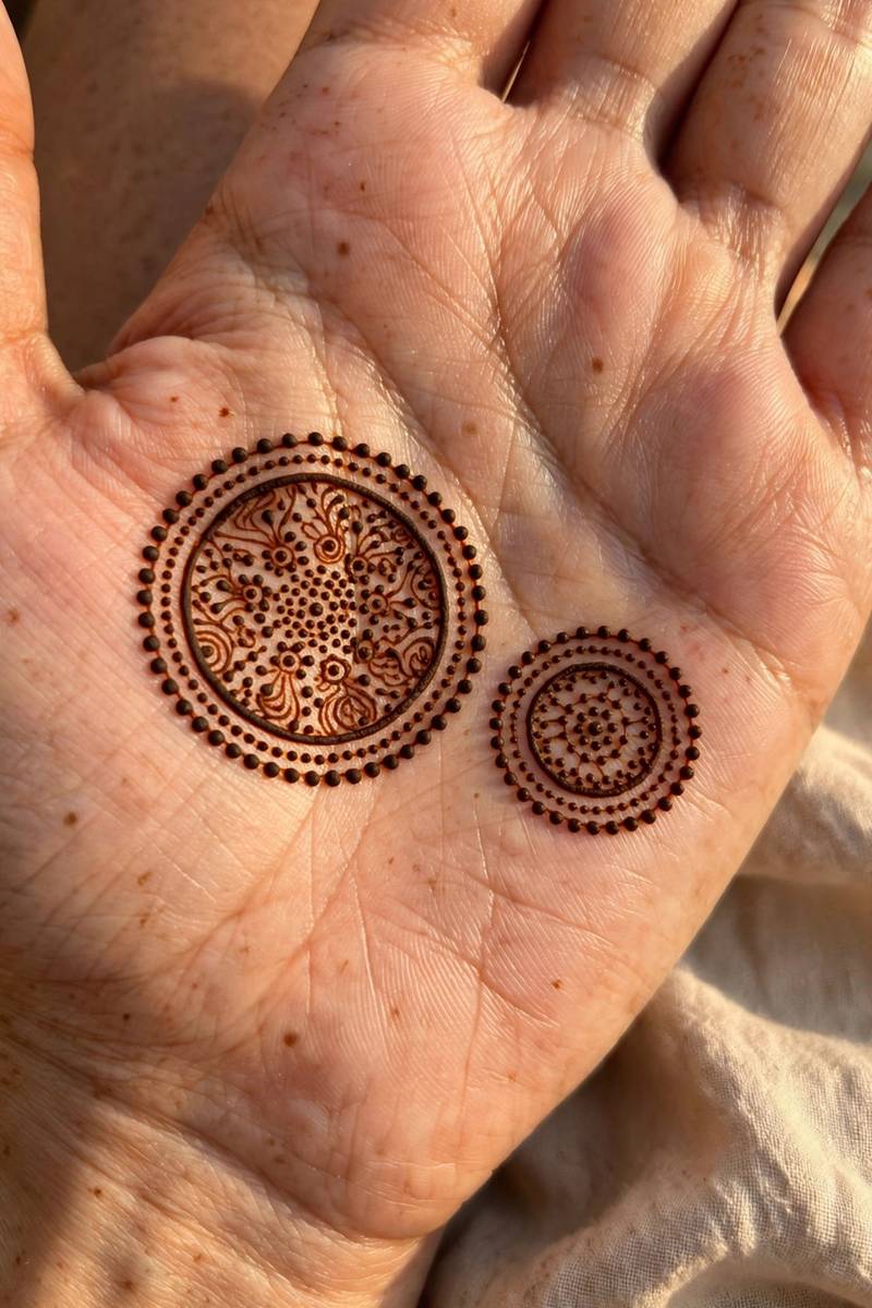 Two tikki mehndi motifs on the palm, one large and one small